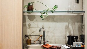A kitchen with a sink, a plant, a coffee maker, and a kettle. - Hotel Føroyar (Tórshavn)