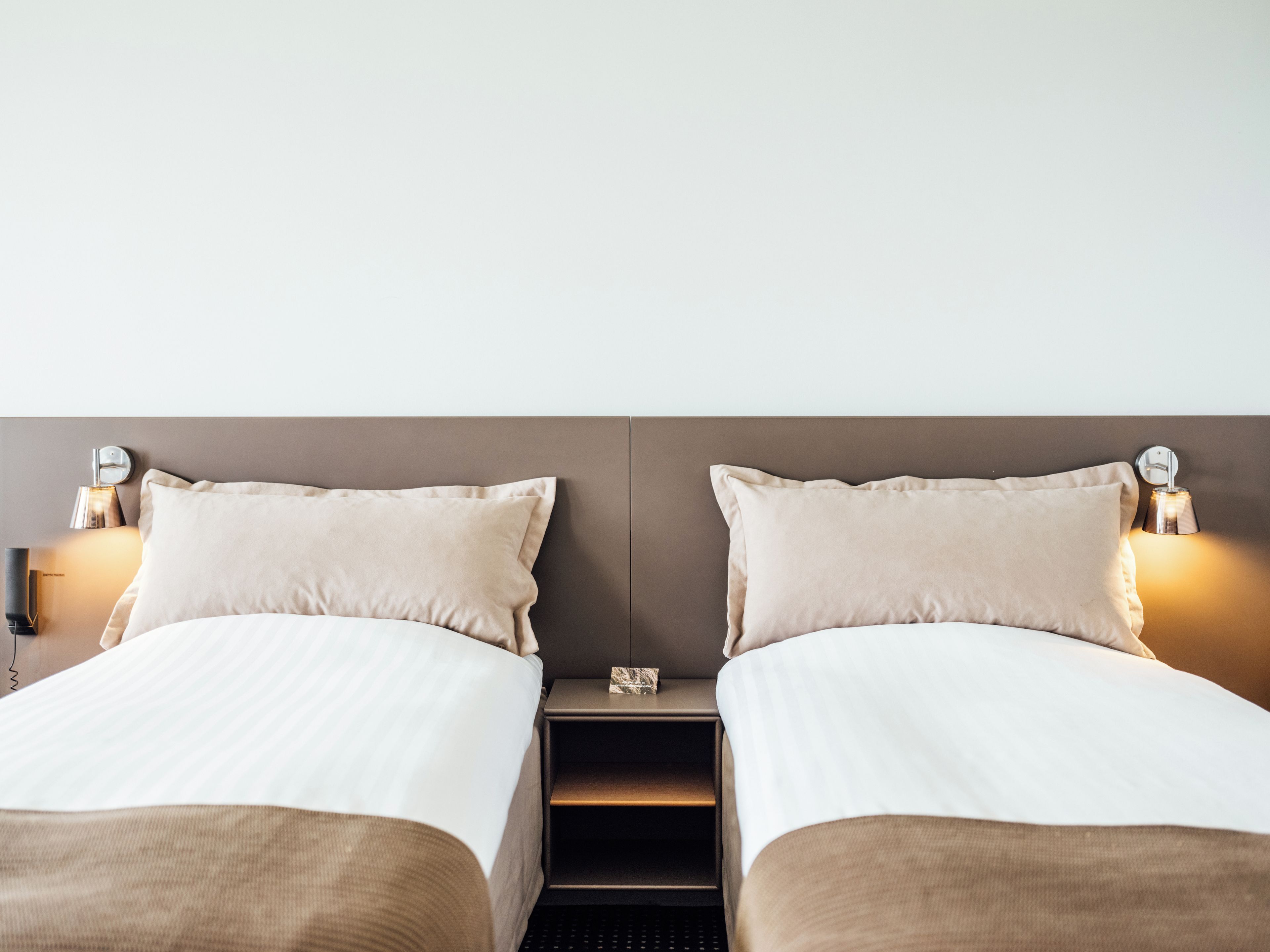 A double bed with a headboard, bedside tables, and wall-mounted lamps.