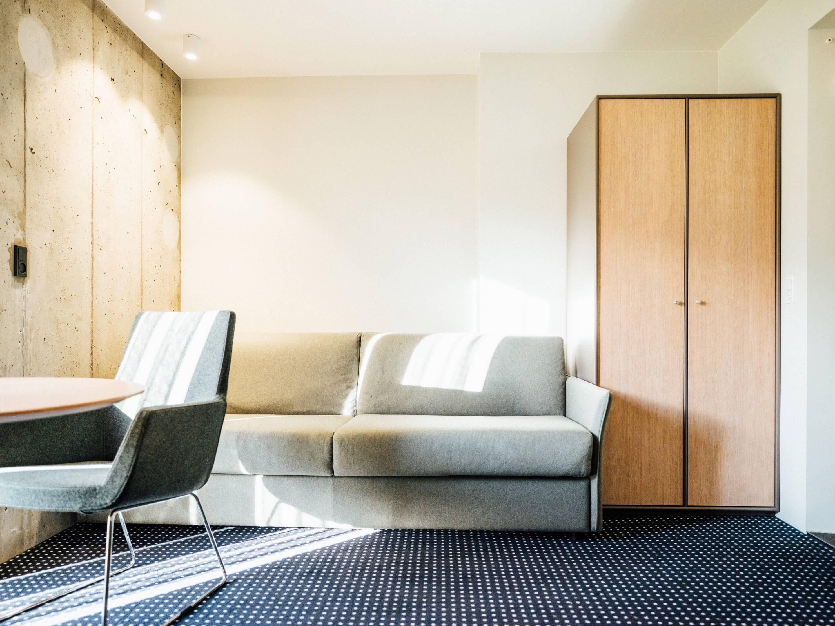Une chambre moderne avec un canapé, une armoire en bois et un tapis à motifs.