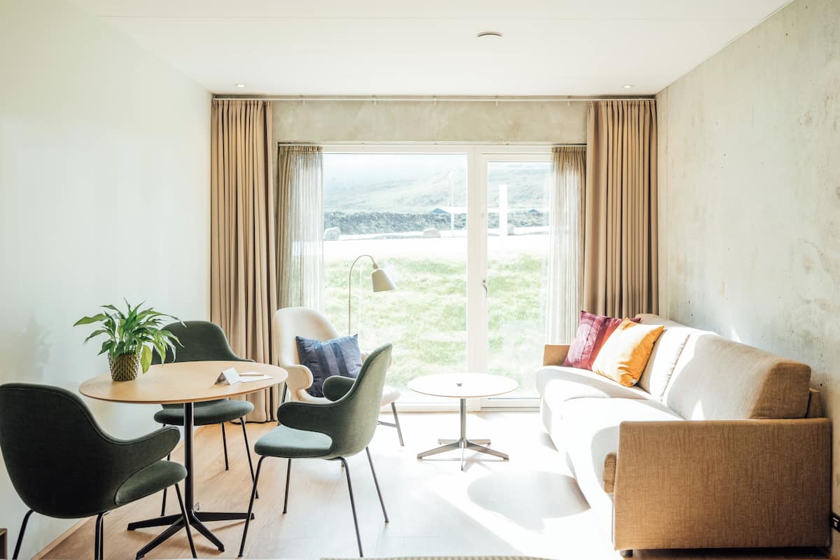 Un salon moderne avec un canapé, des fauteuils, une petite table et une plante.