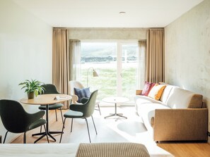 A modern living room with a sofa, chairs, a small table, and a plant.