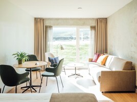 Una sala de estar moderna con un sofá, sillas, una mesita y una planta.