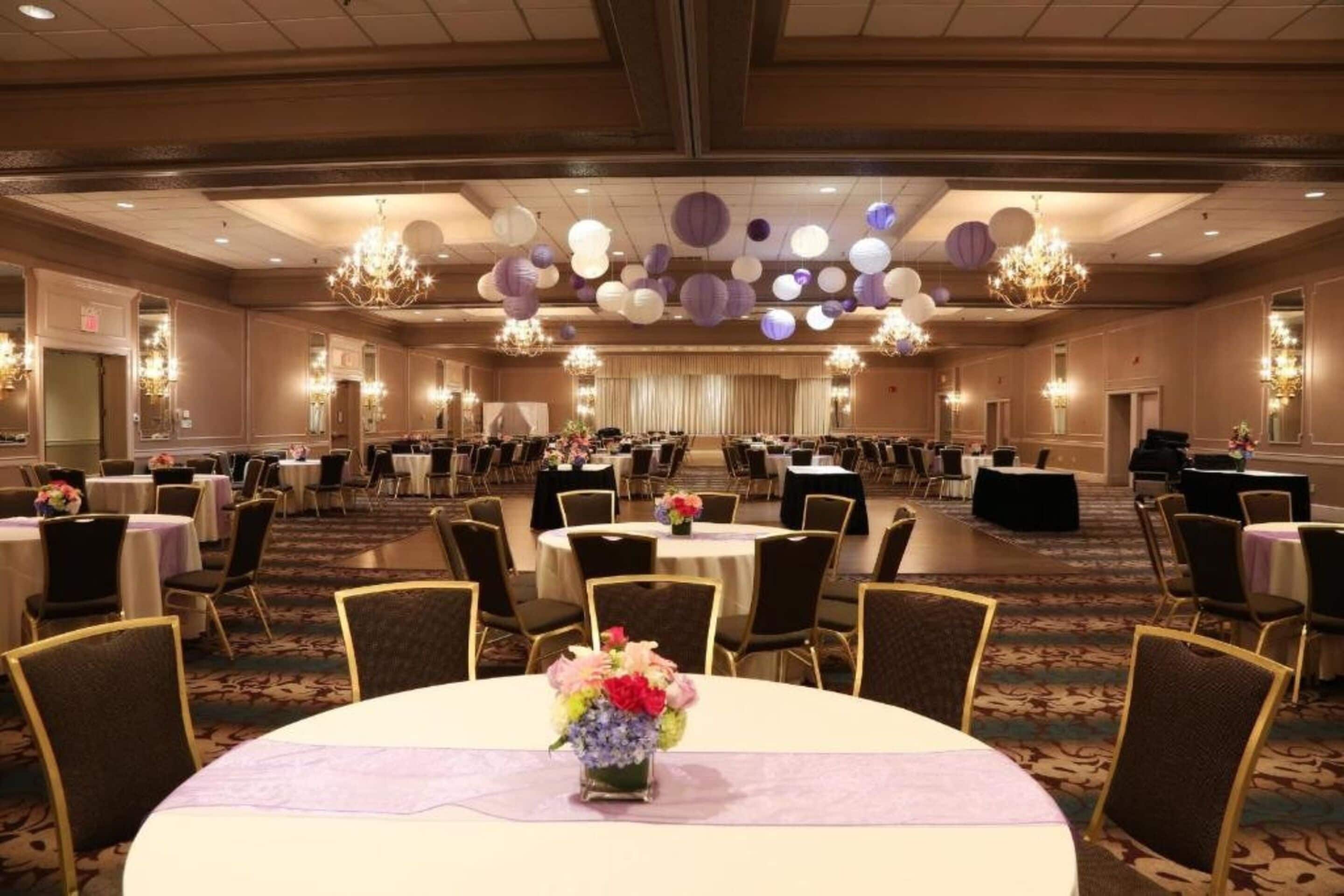 Un salón de banquetes con mesas redondas, sillas y candelabros.