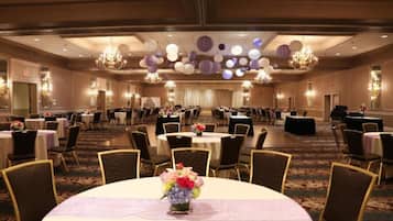 Un salón de banquetes con mesas redondas, sillas y candelabros.