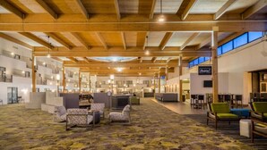 A spacious lobby with a patterned carpet, wooden ceiling beams, and seating areas. - enVision Hotel & Conference Center Mansfield-Foxboro (Mansfield)