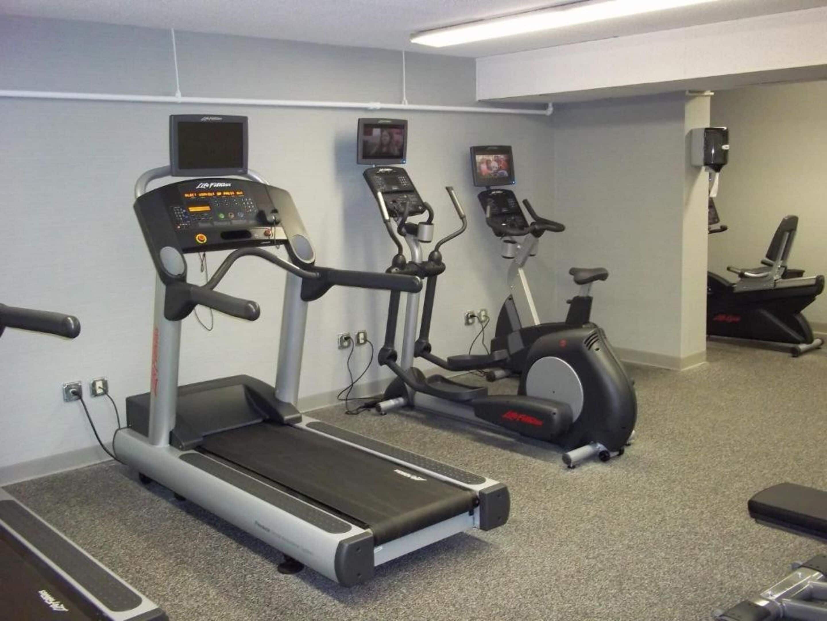 A gym with treadmills, elliptical machines, and a stationary bike.