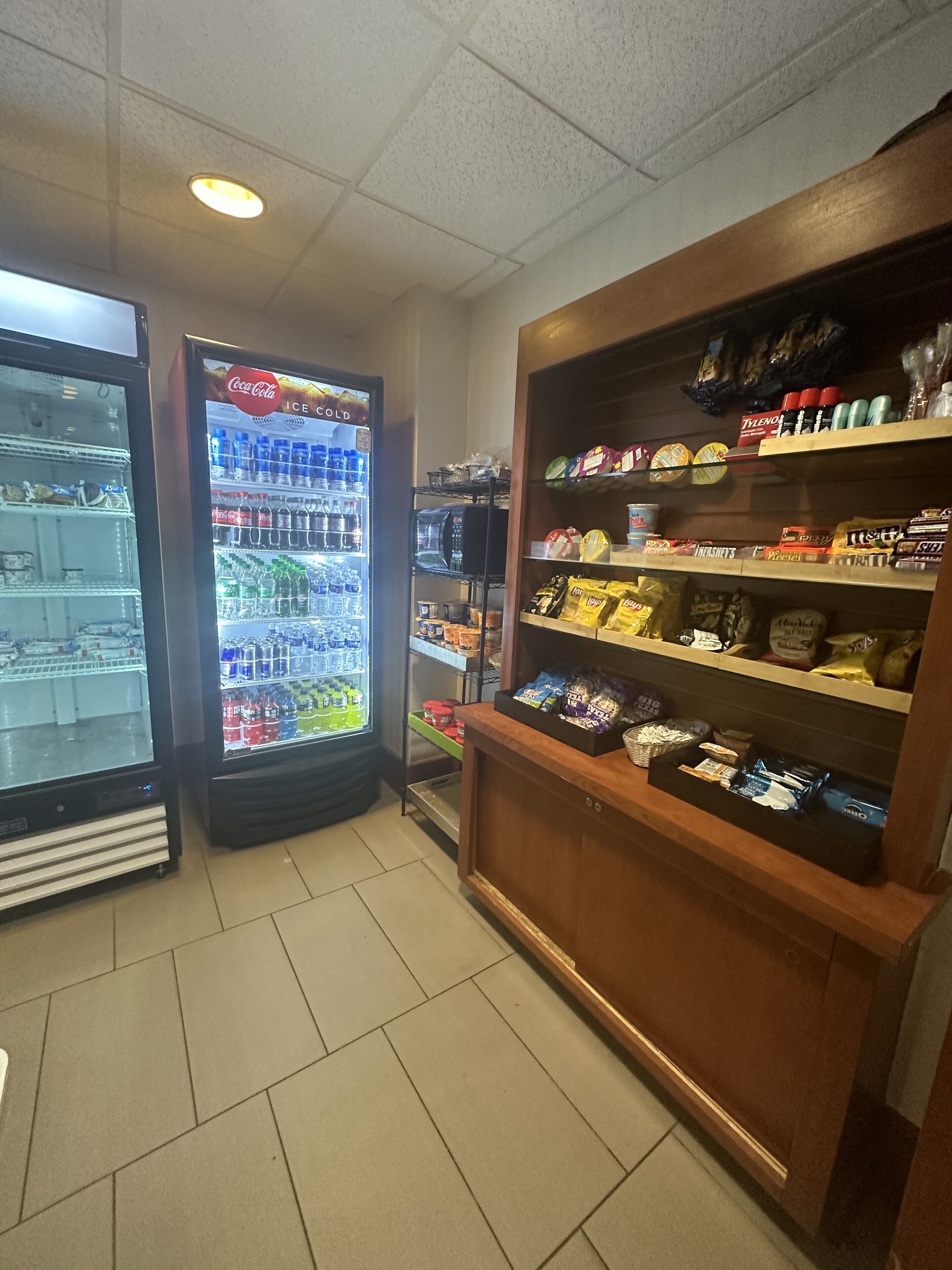 A snack display with various packaged goods, a Coca-Cola refrigerator, and a freezer.