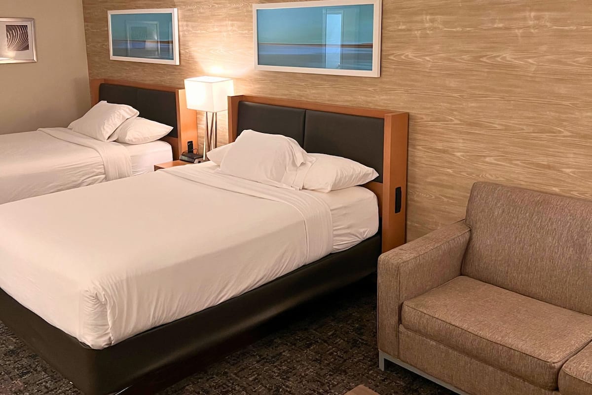 Ein Hotelzimmer mit zwei Betten, einer Couch und Bildern an den Wänden.