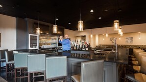 A bar area with seating, a bartender, and a well-stocked bar. - enVision Hotel & Conference Center Mansfield-Foxboro (Mansfield)