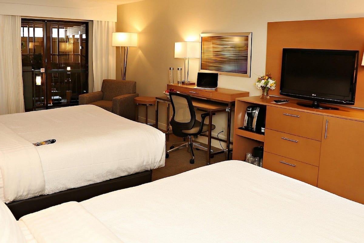 Ein Hotelzimmer mit zwei Betten, einem Schreibtisch mit Computer, einem Fernseher und einer Minibar.