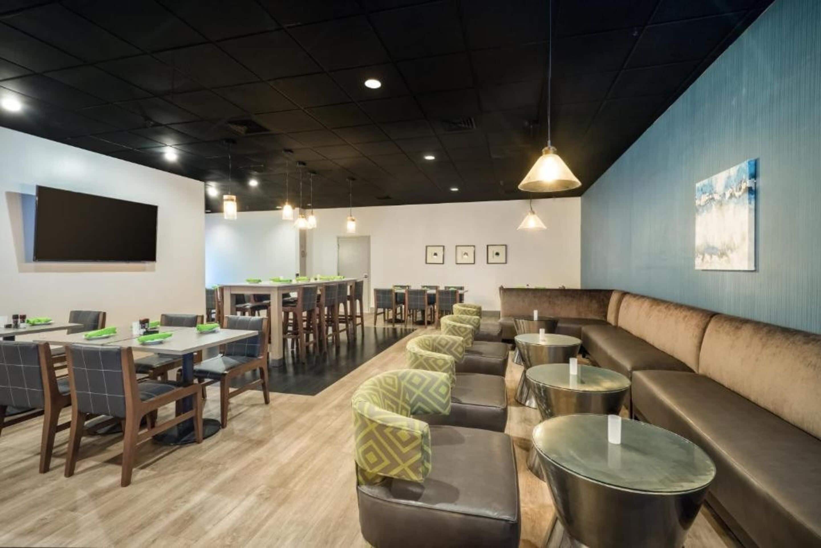 A modern restaurant with a long counter, booths, and a bar area.