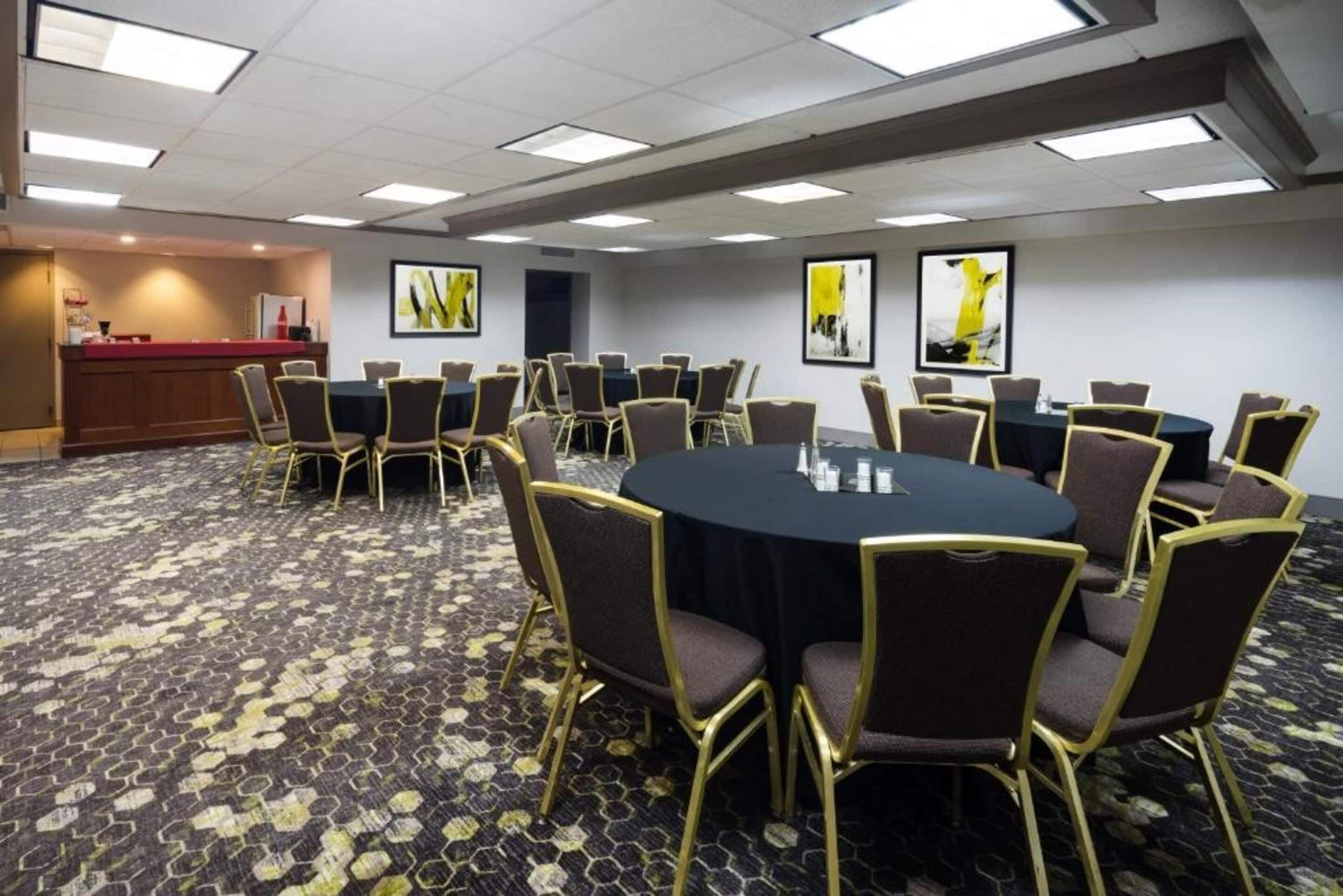 Una sala de conferencias con una mesa redonda, varias sillas y suelo alfombrado.