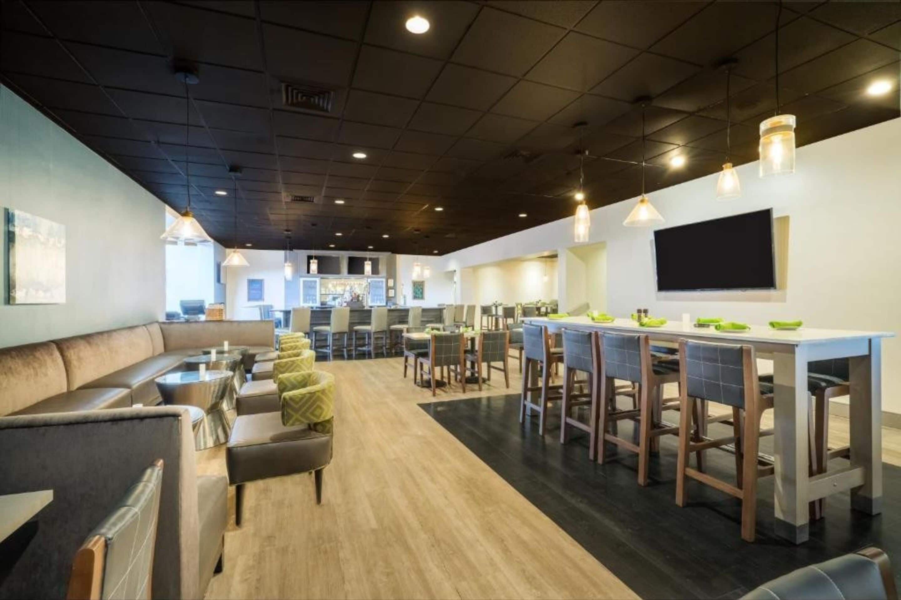 Un restaurante moderno con barra, mesas y una televisión de pantalla plana en la pared.