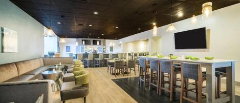 Un restaurante moderno con barra, mesas y una televisión de pantalla plana en la pared.