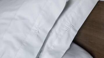 Un coussin blanc orné d’un motif délicat brodé sur une surface en bois.