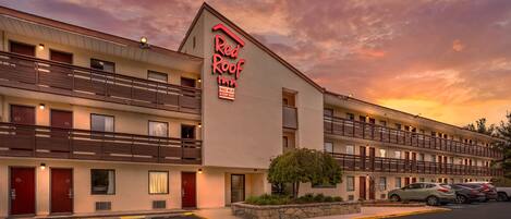 Un hotel Red Roof Inn con una estructura de dos pisos, varios balcones y un estacionamiento.