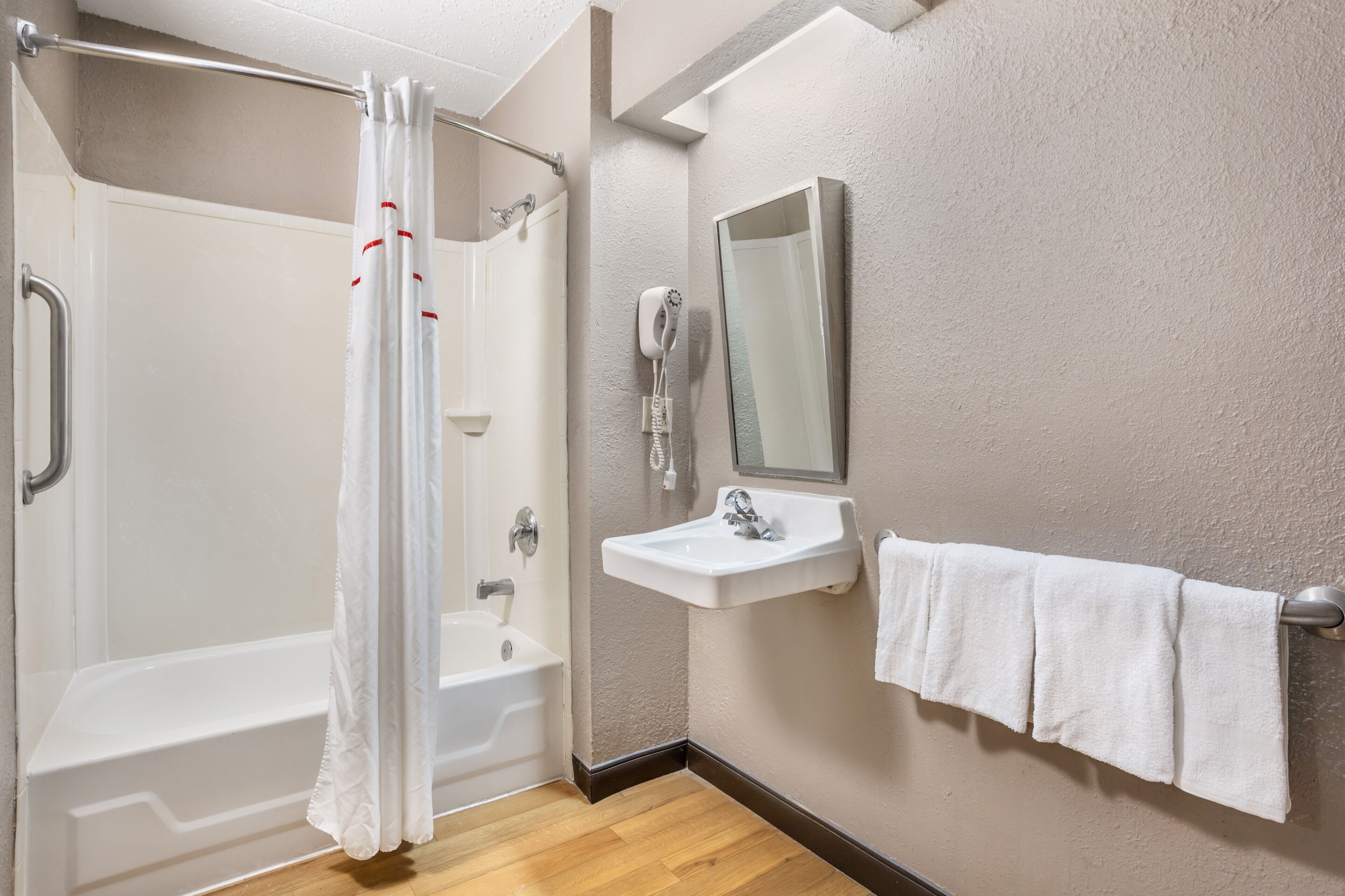 A bathroom with a bathtub, a shower, a sink, and a towel rack.