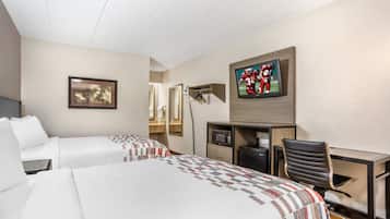 Een hotelkamer met twee bedden, een bureau, een stoel, een televisie en een spiegel.