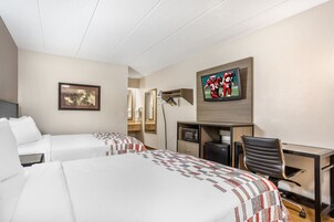 Habitación de hotel con dos camas, un escritorio, una silla, un televisor y un espejo.