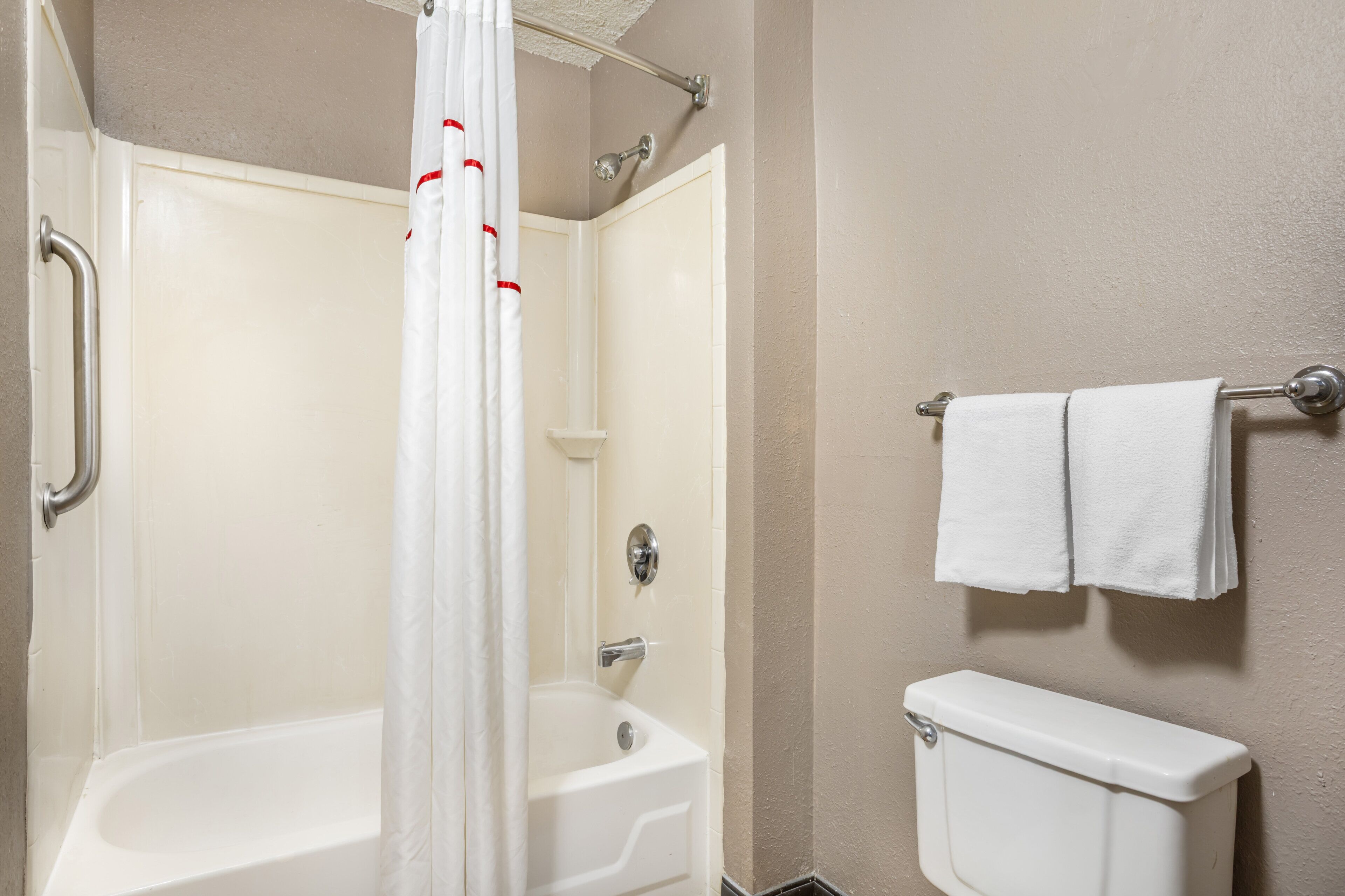A bathroom with a bathtub, shower, toilet, and a towel rack.