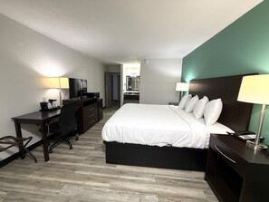 A hotel room with a bed, desk, chair, and a mirror. - Baymont Inn & Suites by Wyndham Newton IA (Newton)