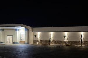 Un edificio con estacionamiento, puerta principal y un banco.