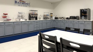 A Baymont Inn & Suites kitchen with a marble countertop, grey cabinets, and a blue carpeted area.