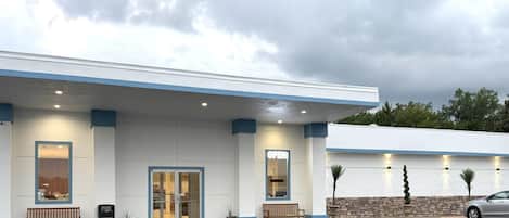 A building with a flat roof, a front entrance, and a parking lot.