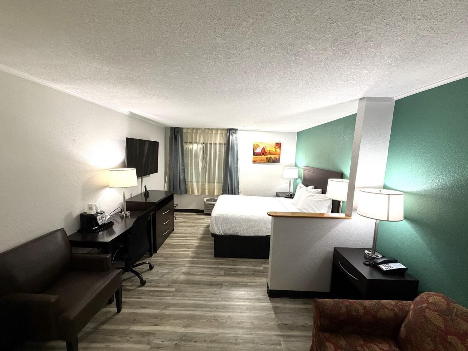 A hotel room with a bed, desk, chair, and a television.