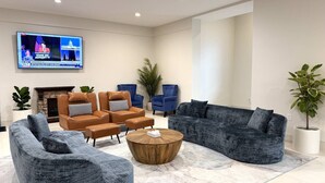 A modern living room with leather sofas, a round coffee table, and a flat-screen TV mounted on the wall.