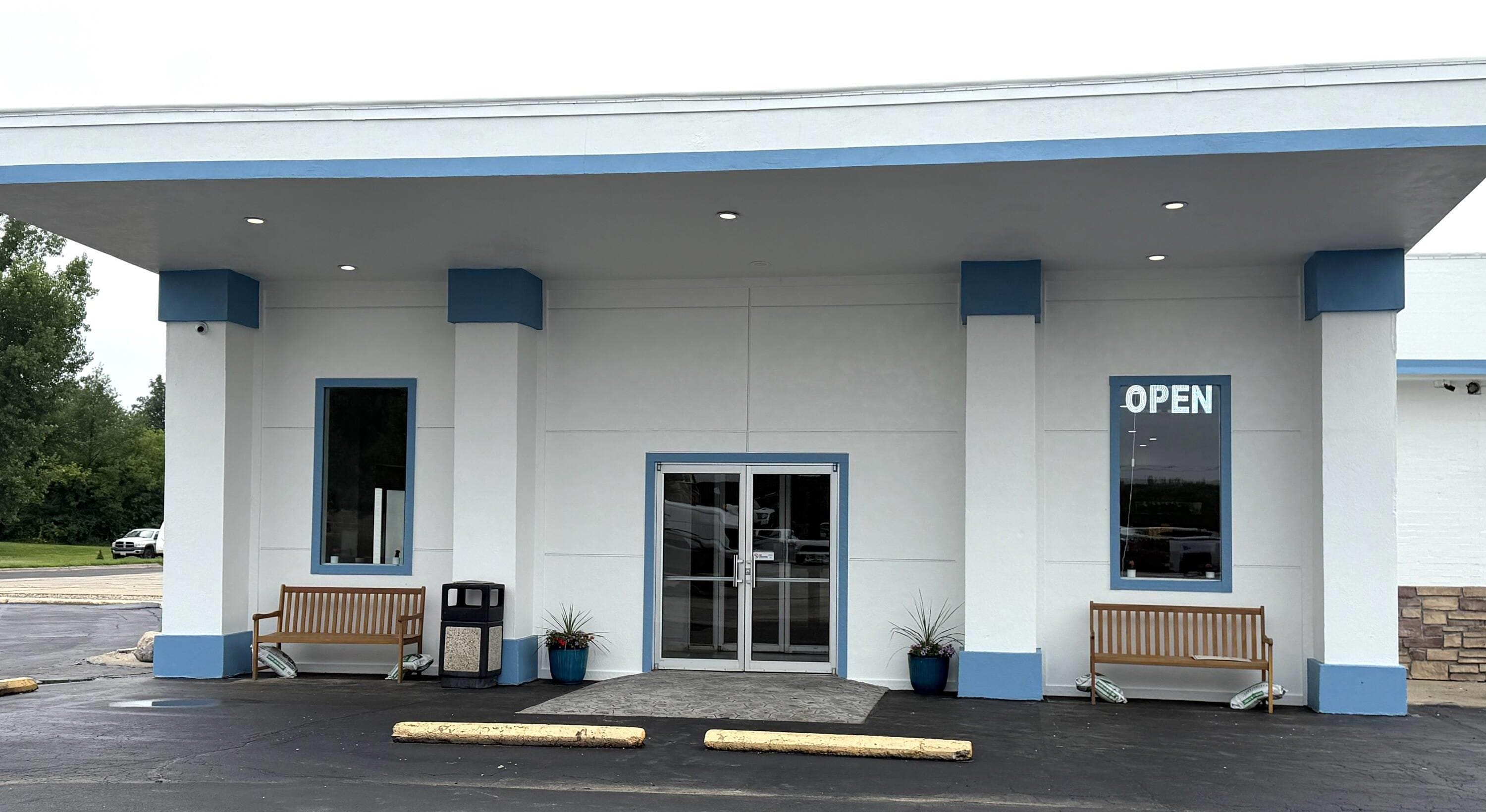 A building with a blue and white facade, a glass door entrance, and a sign that reads 'OPEN'.