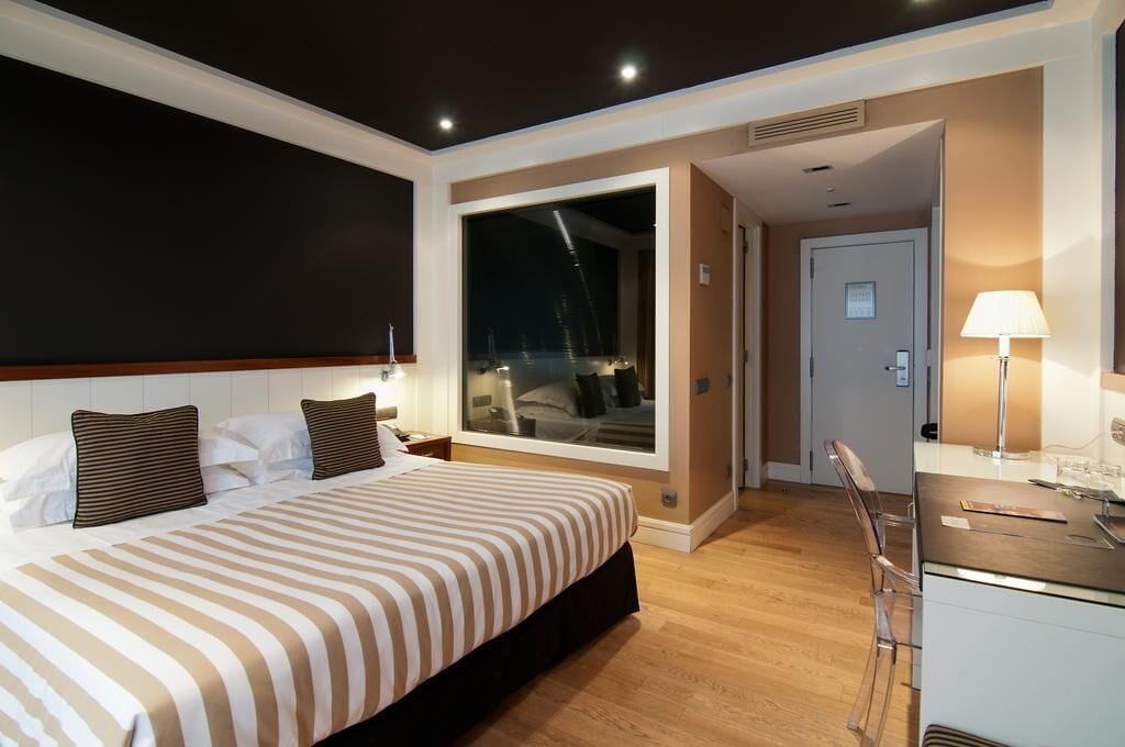 Habitació d'hotel amb un llit gran, escriptori, cadira i vista del cel nocturn.