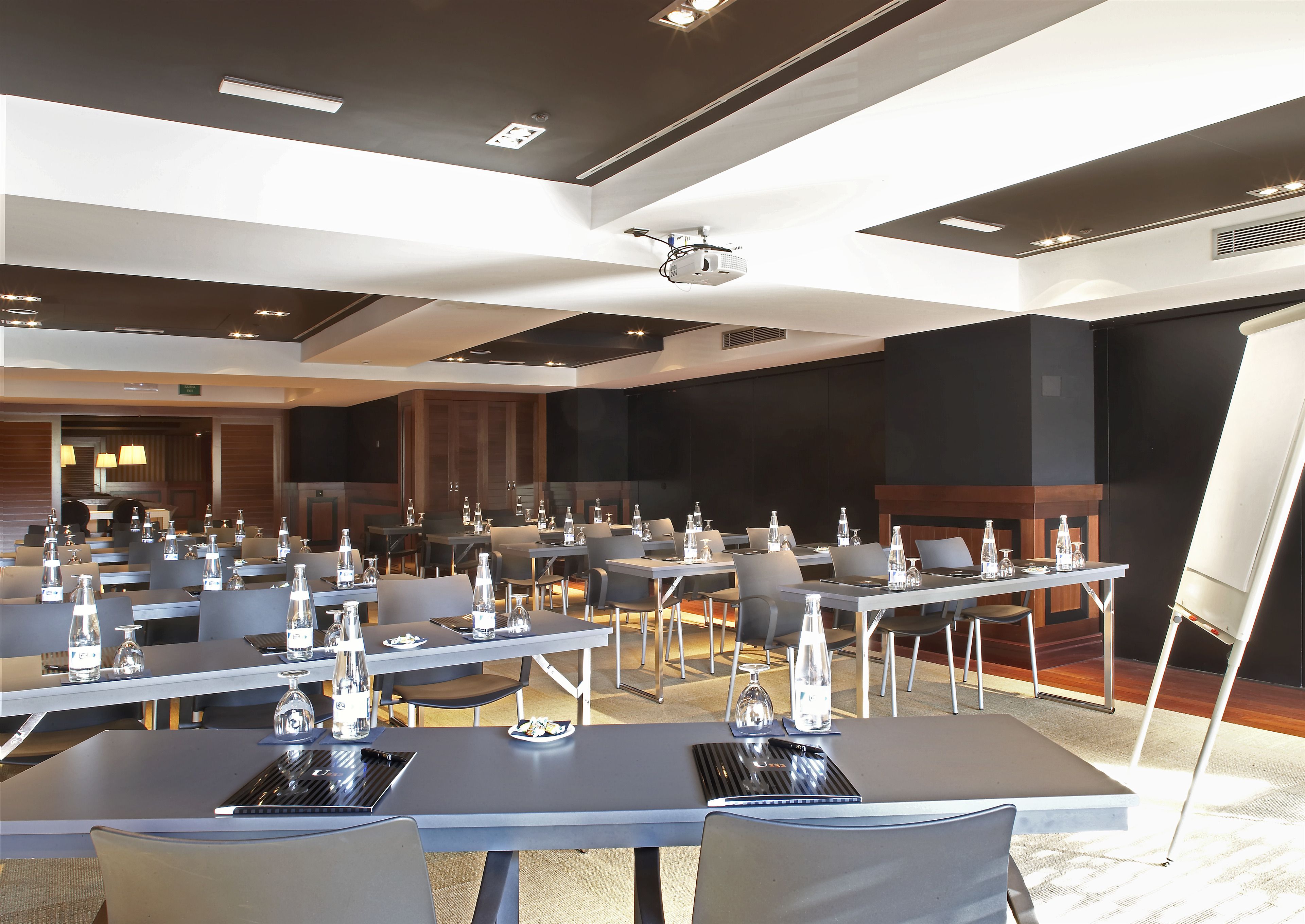 A conference room with multiple tables, chairs, and a projector screen.