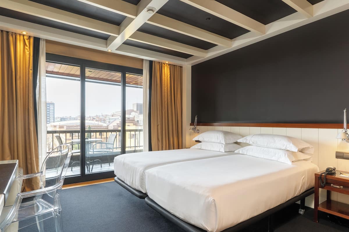 Habitación de hotel con dos camas, un escritorio y una silla.