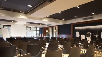 A conference room with rows of chairs, a projector screen, and a display of formal wear.