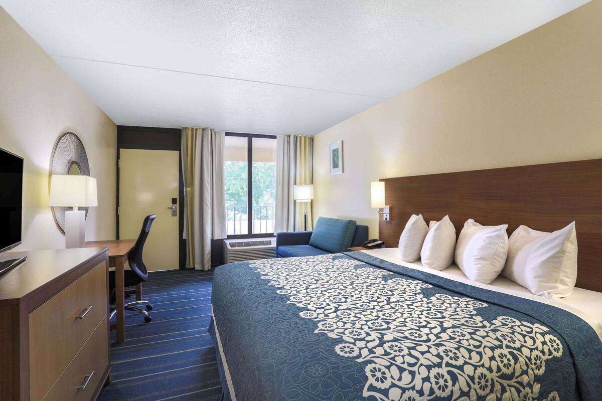 Hotelkamer met een bed, bureau, stoel, televisie en uitzicht op de omgeving.