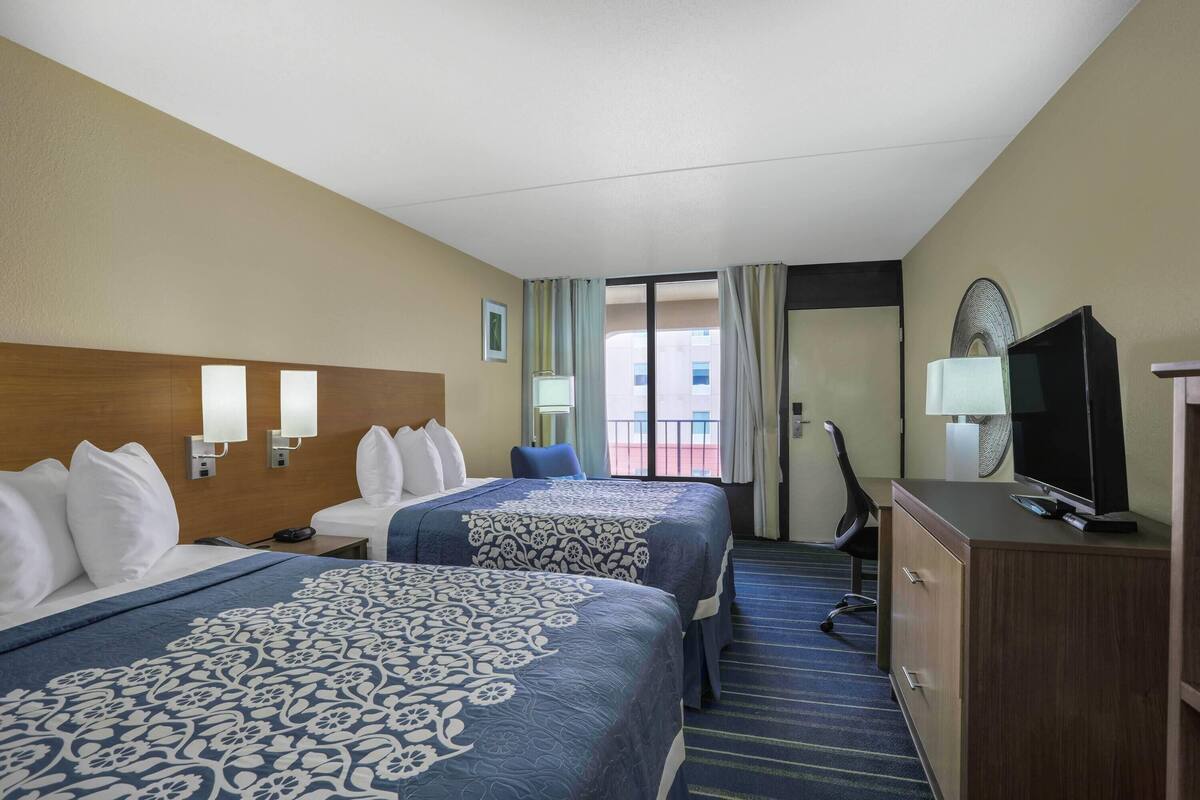 Een hotelkamer met twee bedden, een bureau, een televisie en uitzicht op het balkon.