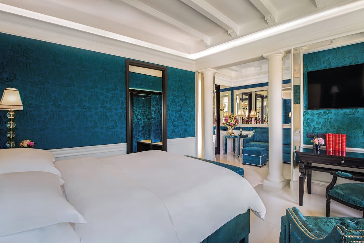 A hotel room with a large bed, a desk with a chair, and a TV.