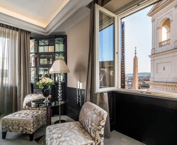 A hotel room with a view of a historic building, a glass table with a lamp, and patterned furniture. - Hassler Roma (Rome)
