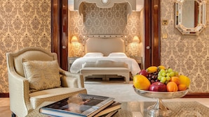 Una habitación de hotel con una cama, una zona de estar con una silla y una mesa, y un frutero sobre la mesa.