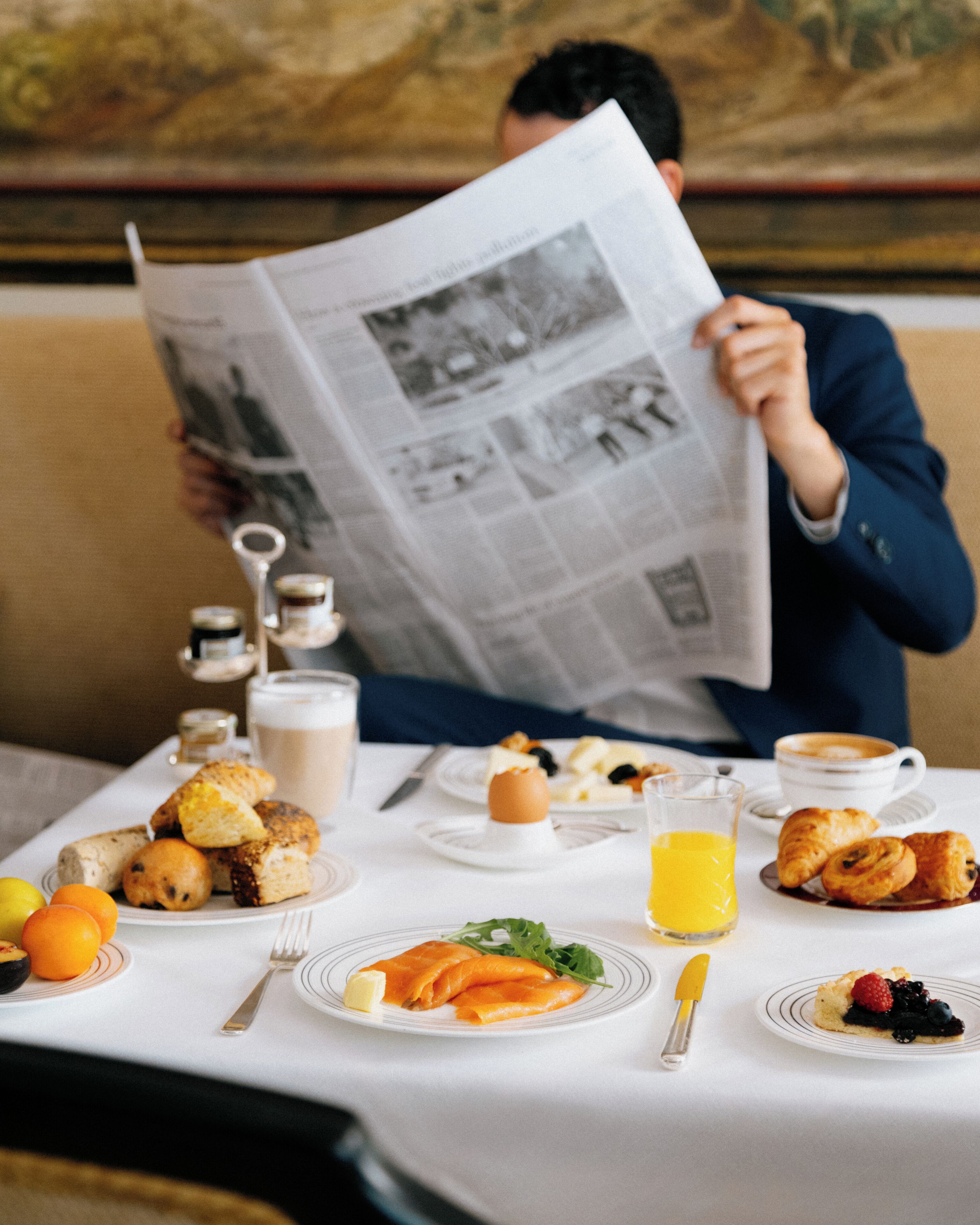 Uma mesa de jantar com itens de café da manhã, um jornal e uma xícara de café.