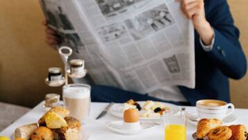 Uma mesa de jantar com itens de café da manhã, um jornal e uma xícara de café.