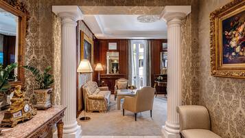 Una sala amplia con papel tapiz decorativo, un espejo grande y muebles clásicos.