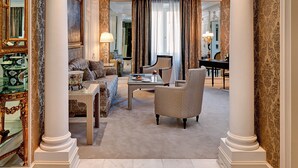 Amplia sala de estar elegantemente amoblada, con un piano de cola, asientos cómodos y columnas decorativas.