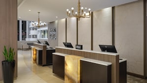 A hotel reception desk with two computers, a chandelier, and a potted plant. - Hilton Washington DC/Rockville Hotel & Executive Meeting Ctr (Rockville)