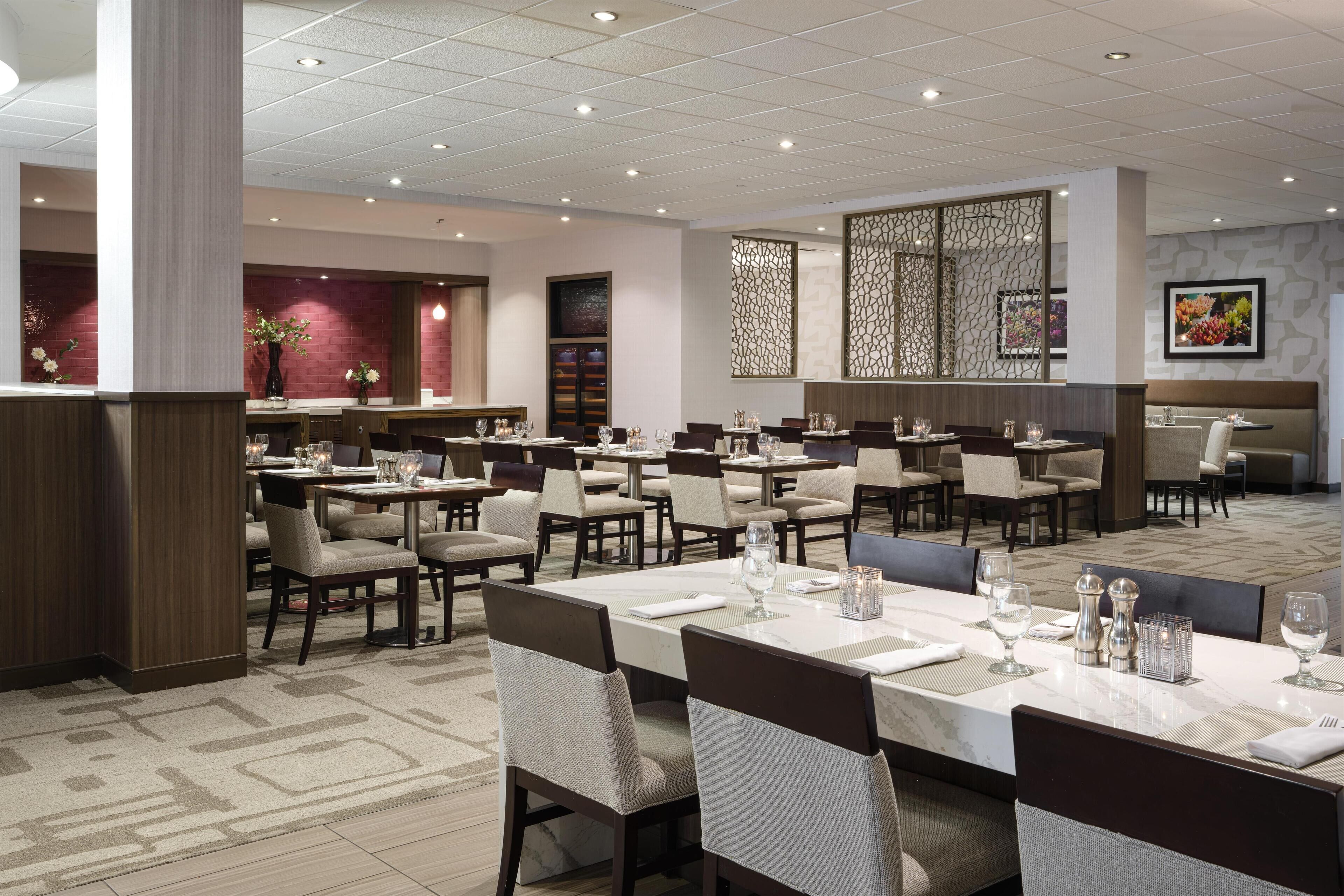 A spacious dining area with multiple tables and chairs, a decorative wall, and a patterned floor.