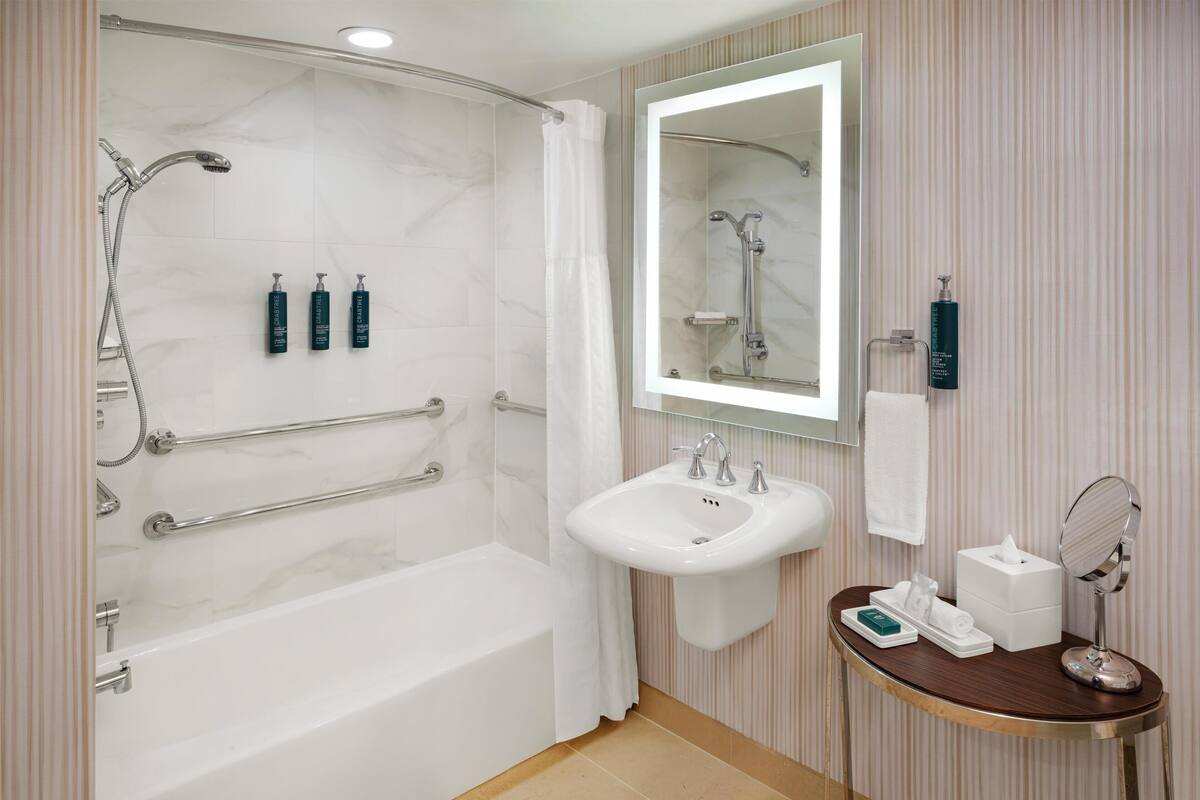 Un baño moderno con bañera, lavabo y tocador con espejo.