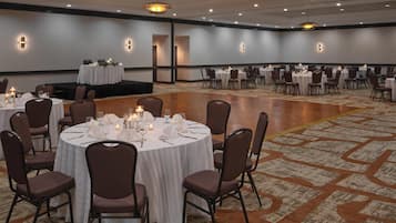 A banquet hall with round tables set for dining, arranged in rows with chairs.