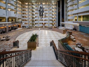 A spacious lobby with a checkered floor, a central seating area, and a staircase leading to upper floors.