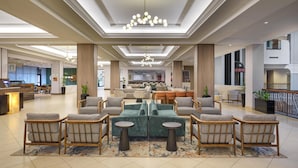 A spacious lobby with a central seating area, a reception desk, and a kitchen in the background. - Hilton Washington DC/Rockville Hotel & Executive Meeting Ctr (Rockville)